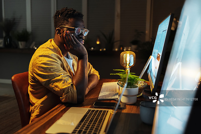 在晚上办公室用电脑工作的有压力的年轻商人图片素材