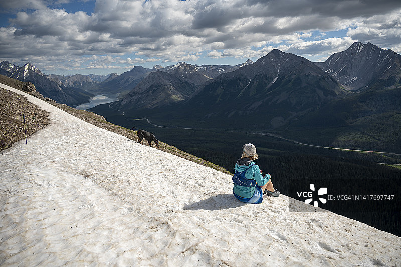 在雪山山脊上放松的女跑步者图片素材