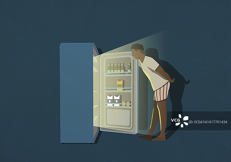 男子晚上站在厨房的冰箱前图片素材