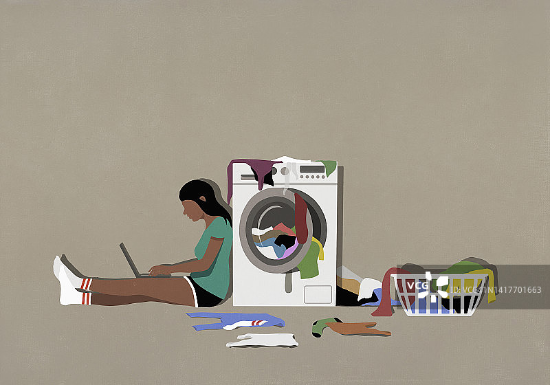 女孩在烘干机旁用笔记本电脑洗衣服图片素材