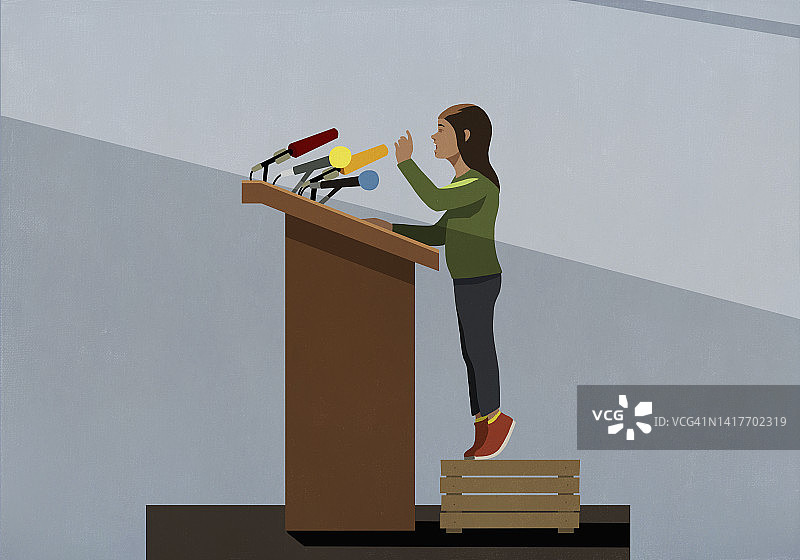 女孩站在板条箱上，在讲台上对着麦克风讲话图片素材