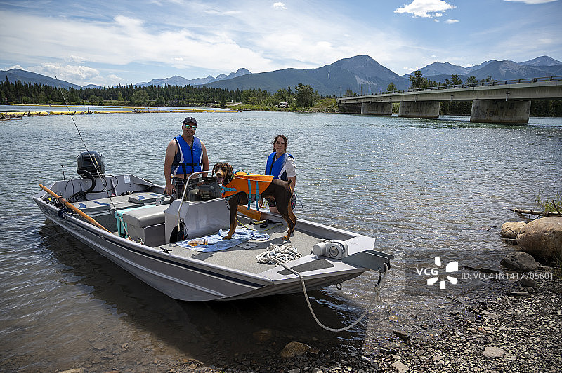 夫妇和狗准备乘摩托艇离开图片素材