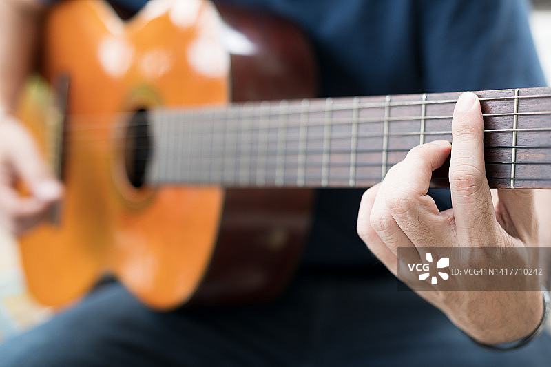 年轻男子在家弹奏原声吉他图片素材