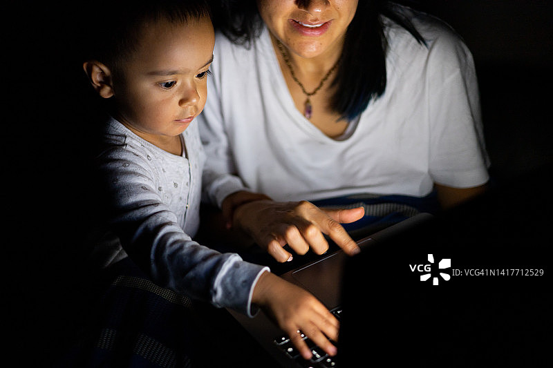 女人和她的孩子在晚上看屏幕图片素材