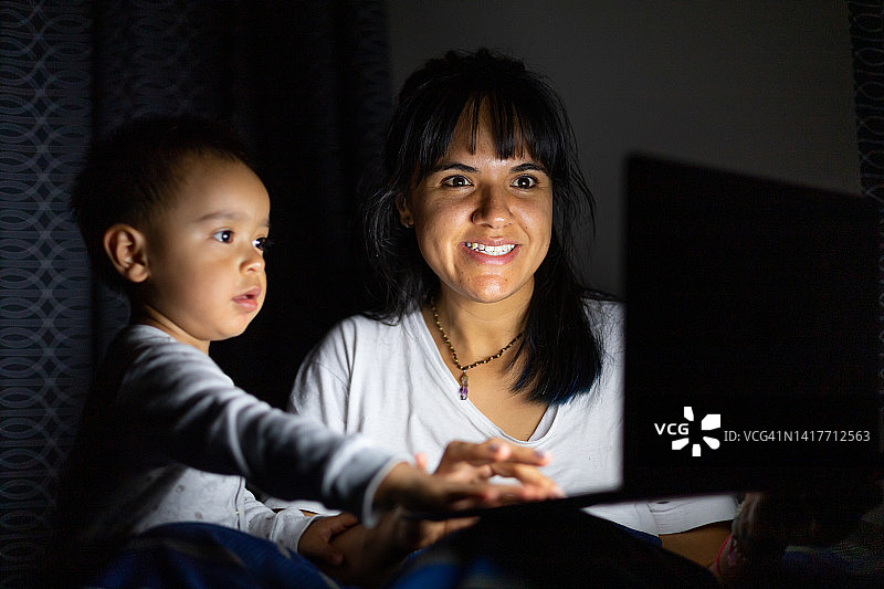 女人和她的孩子在晚上看屏幕图片素材