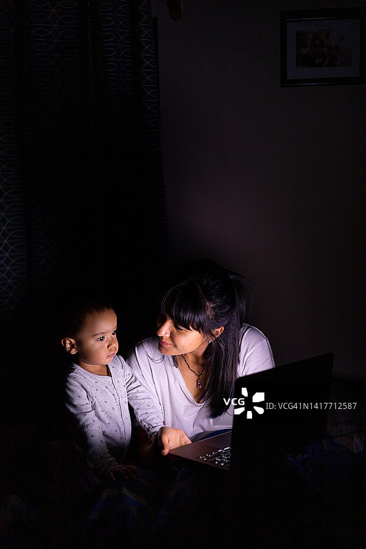 女人和她的孩子在晚上看屏幕图片素材