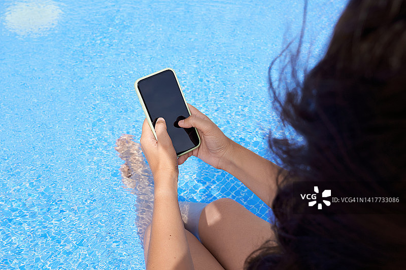 在泳池边查看手机的女子图片素材