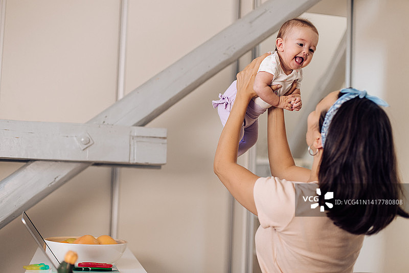 女子抱着婴儿操作笔记本电脑图片素材