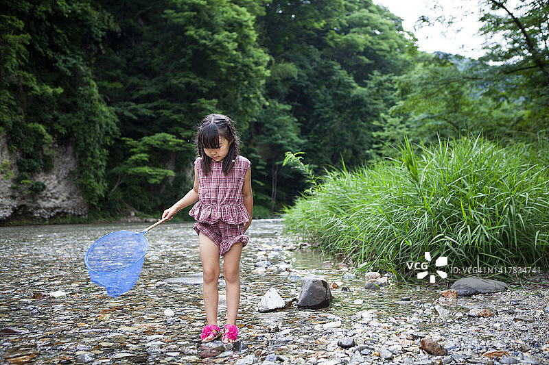 可爱的小女孩用网在小溪里抓鱼图片素材