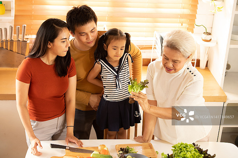 亚洲大家庭准备健康食品并用智能手机自拍图片素材