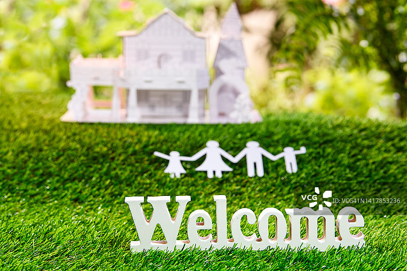 绿色草地上的纸质家庭和房屋背景欢迎图图片素材