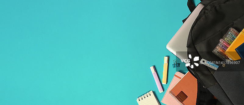 浅蓝色背景上的学校文具和背包，留有复制空间，返校概念图片素材
