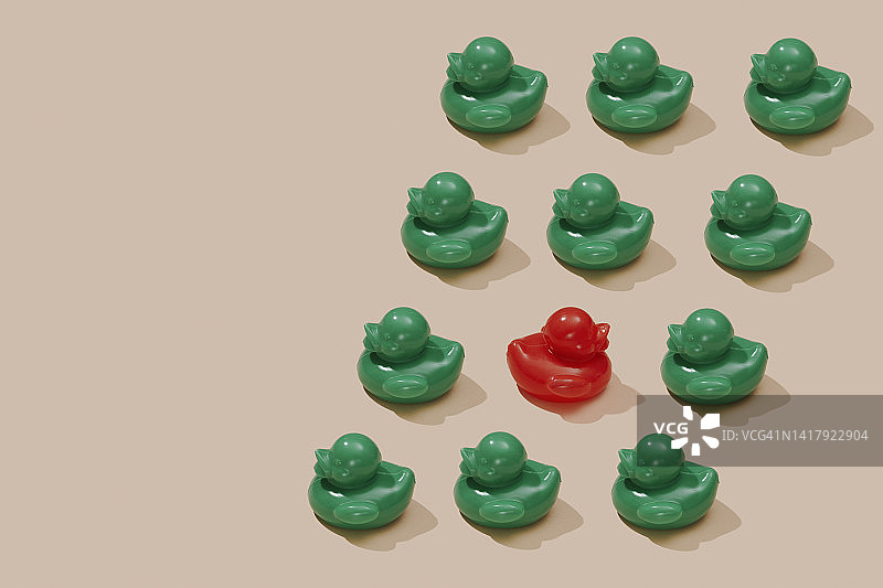 红色橡皮鸭在一些绿色橡皮鸭之间逆流而上图片素材