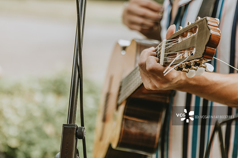 身穿彩色条纹衬衫的音乐家在户外弹吉他图片素材