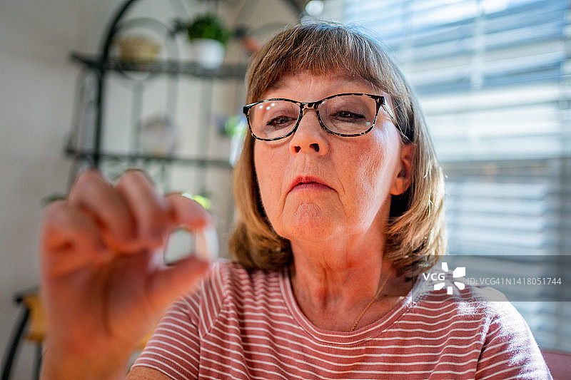 在家阅读处方瓶管理自己健康的中年妇女图片素材