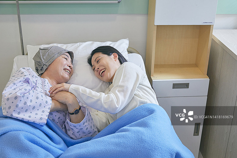 微笑的母女躺在病床上，彼此对视图片素材