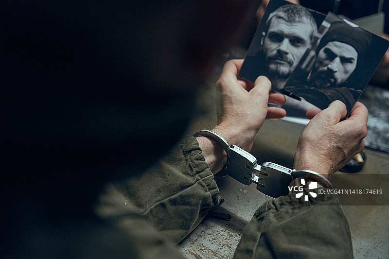 戴着手铐的手与专业照明下的嫌疑人黑白照片图片素材