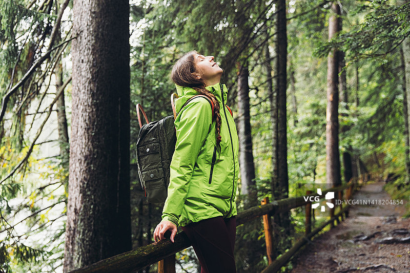 背着背包的女人在风景如画的森林中漫步，思考秋日图片素材