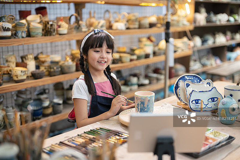 正在彩绘泥土杯子的(8-9岁)小女孩图片素材