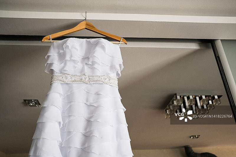 木制衣架上用于婚纱或晚礼服的豪华昂贵现代时尚优雅婚纱和面纱。早晨的聚会和准备，为新娘穿衣。美丽的客厅内饰。婚礼当天。图片素材