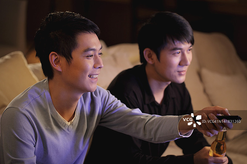 一起看电视的年轻男人，面带微笑图片素材