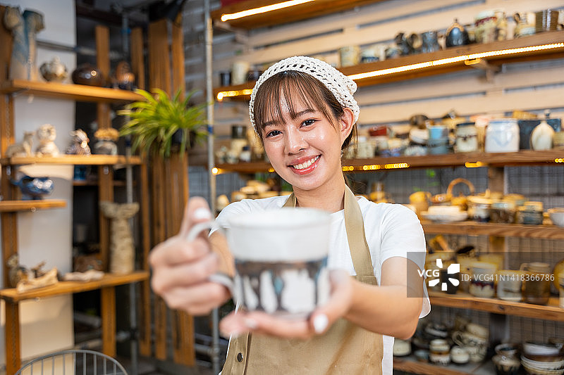年轻的亚洲女陶艺家在陶艺工作室直播竞拍手工陶瓷制品图片素材