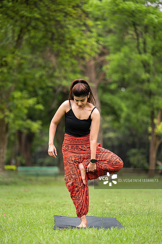 树式瑜伽。身材苗条的女子练习瑜伽，单腿站立，呈合十礼姿势图片素材