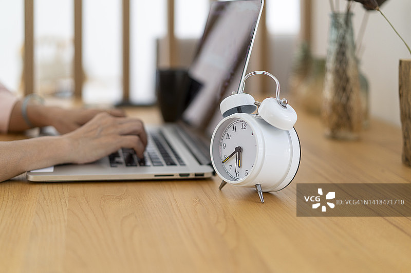 书桌上的闹钟和笔记本电脑图片素材