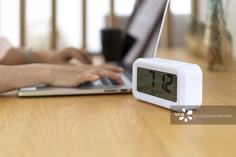 书桌上的闹钟和笔记本电脑图片素材