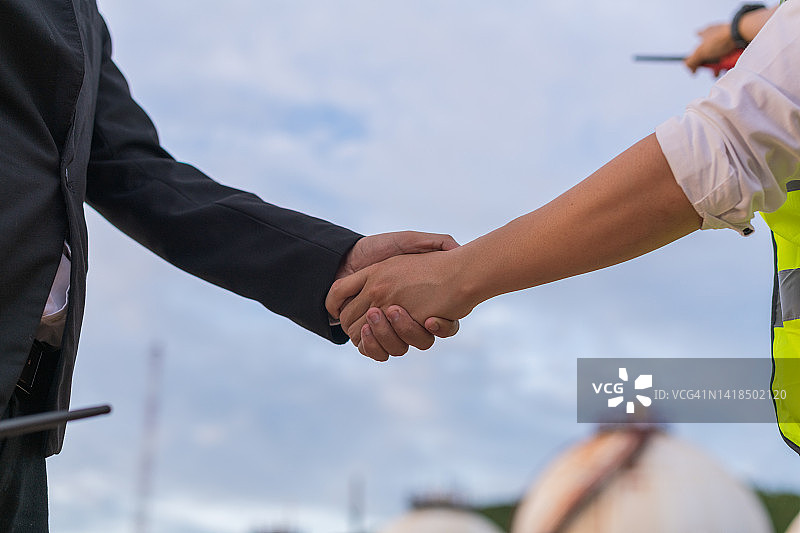 年轻商人和工程师握手：炼油厂工业的商业成功，炼油厂商业背景概念图图片素材