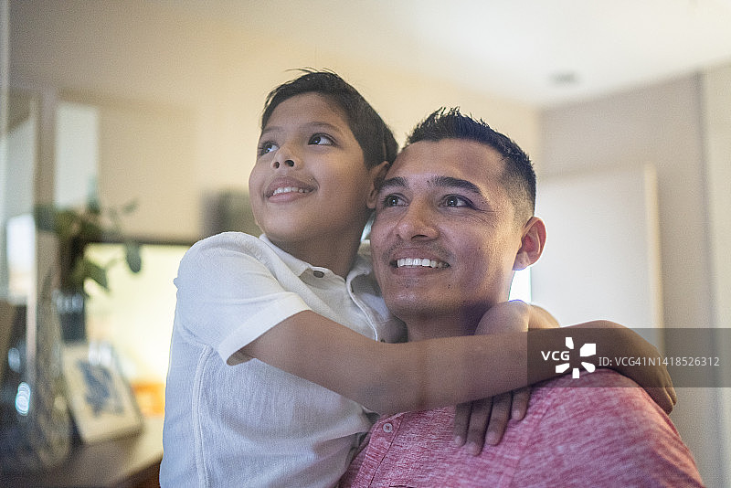 父亲扛着儿子，抬头看着家图片素材