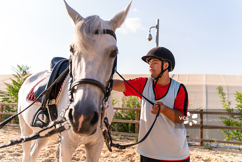 快乐的患有唐氏综合症的年轻男人爱抚着马图片素材