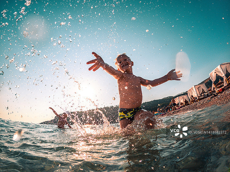 在暑假里举起手臂戏水的可爱儿童图片素材