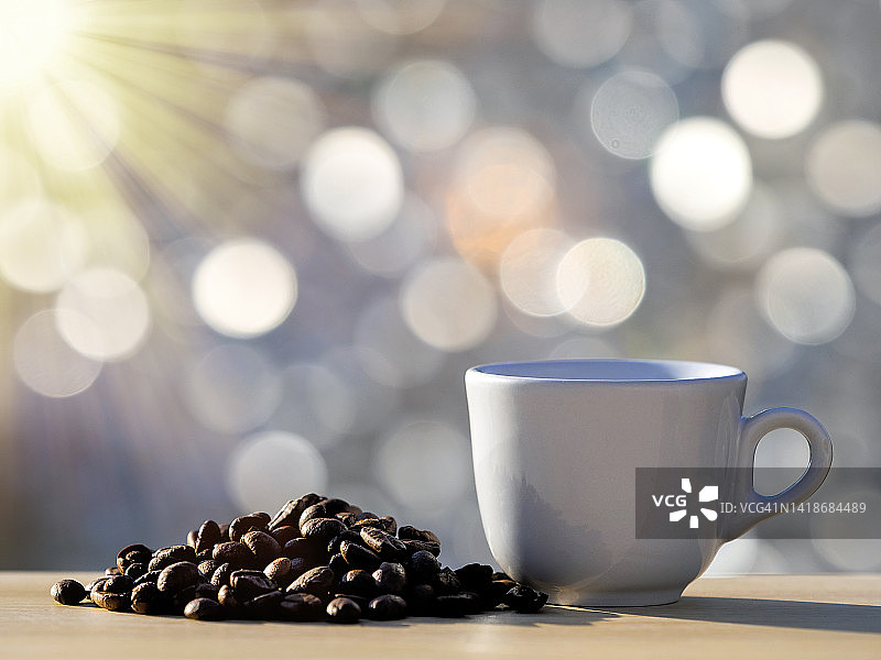 阳光下的烘焙咖啡豆和咖啡杯早餐图片素材