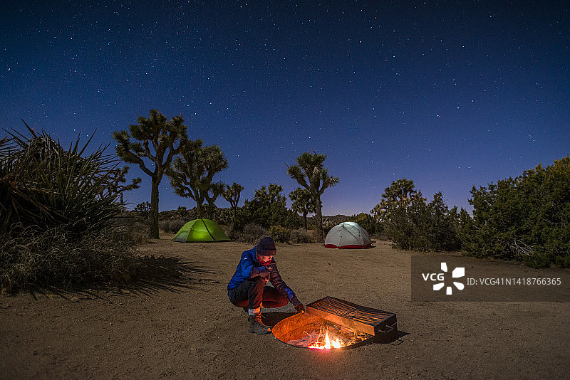 在约书亚树国家公园，女人在帐篷附近拨弄篝火图片素材