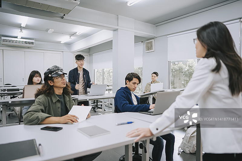亚洲大学生在课堂问答环节回答讲师问题图片素材