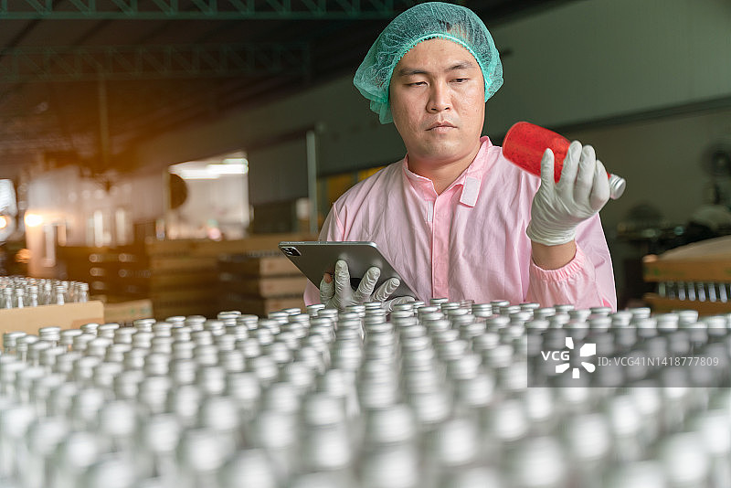 男工人在饮料厂检查罗勒籽饮料的质量图片素材