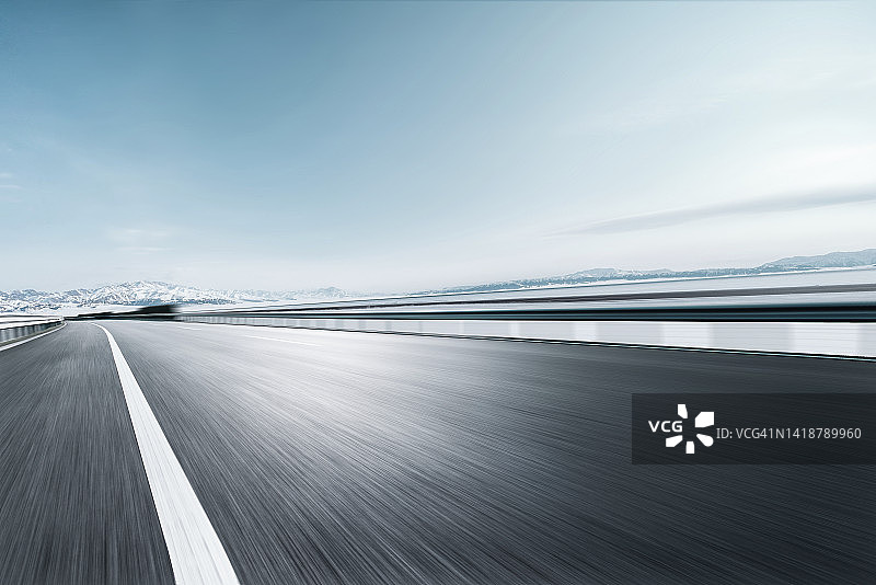 雪山旁冰封湖面高速公路的广角模糊视图图片素材