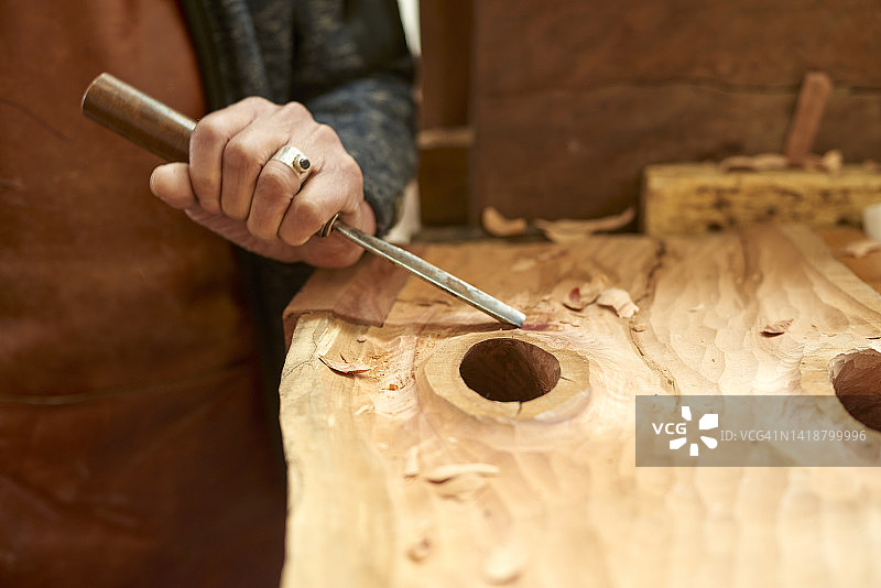 年长者在一块带结的木头上雕刻图片素材