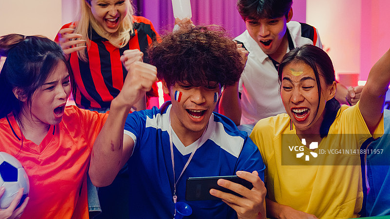 亚洲青少年在沙发上看手机上的世界杯足球赛图片素材