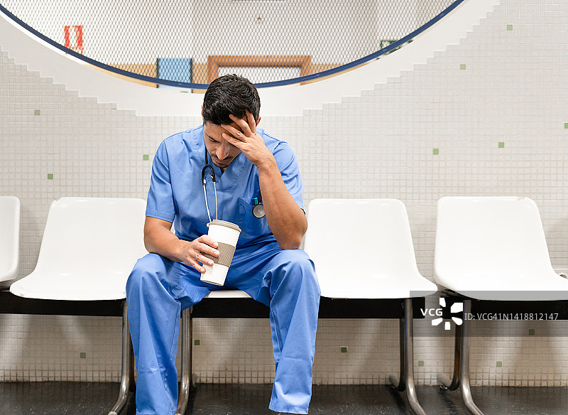 疲惫的医生在等候室里拿着外卖咖啡图片素材