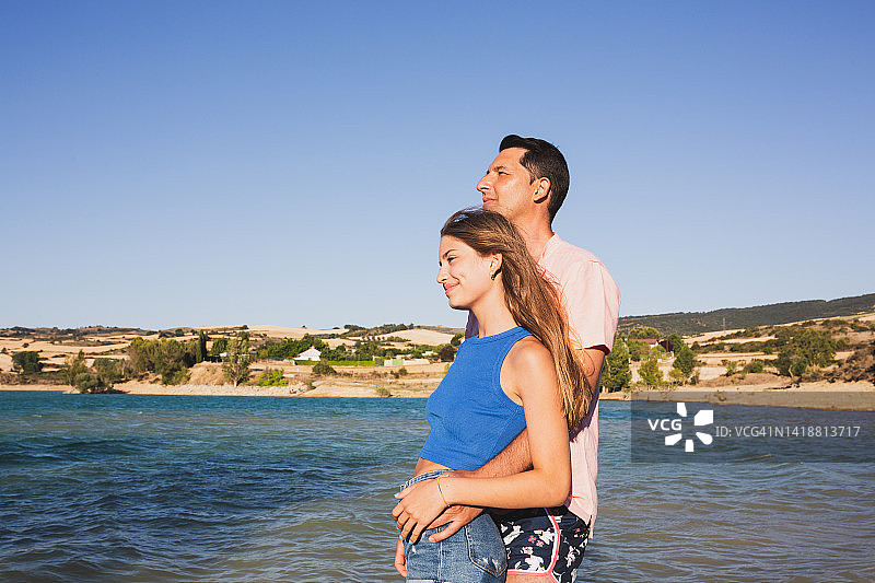 爸爸在湖边拥抱可爱的女儿图片素材