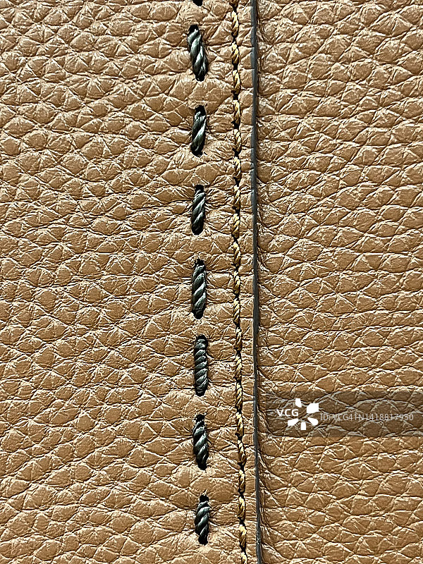 手提包上用两种机器针迹缝合的两块棕色皮革材料图片素材