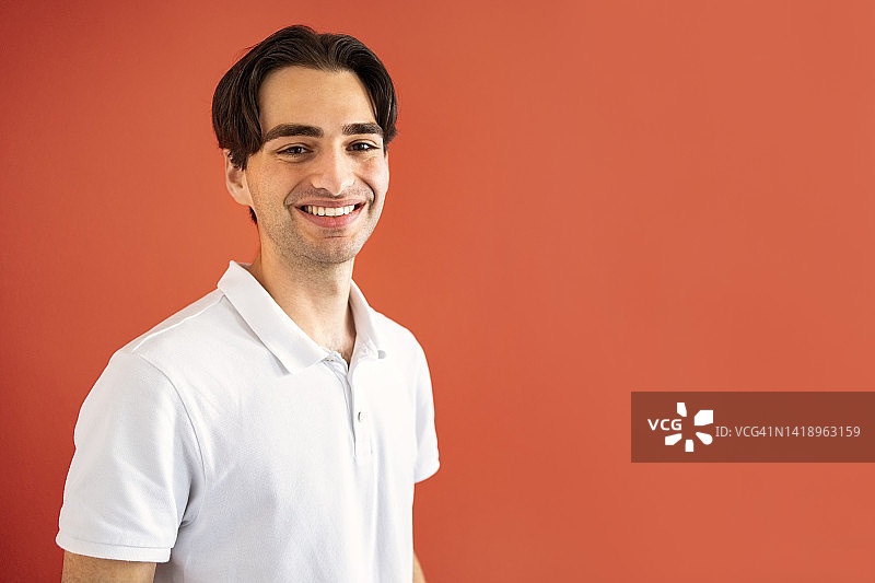 橙色背景下的微笑青年图片素材