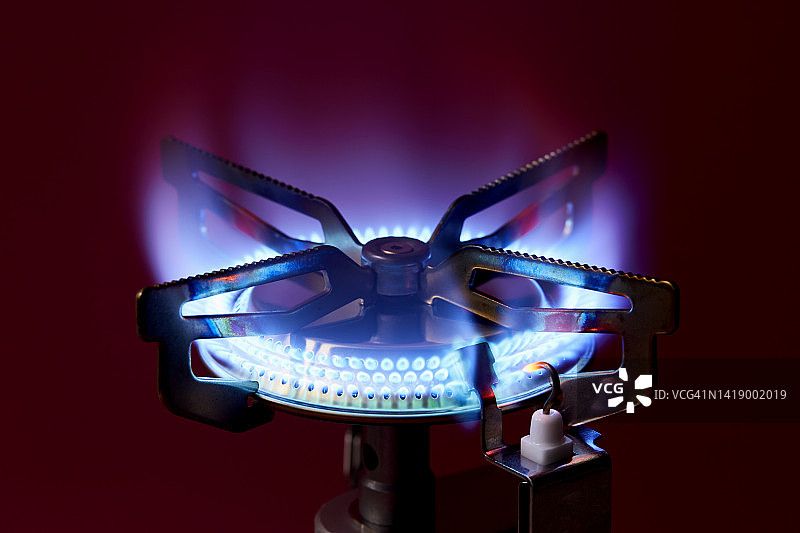 红色背景上的燃气灶燃烧特写图片素材