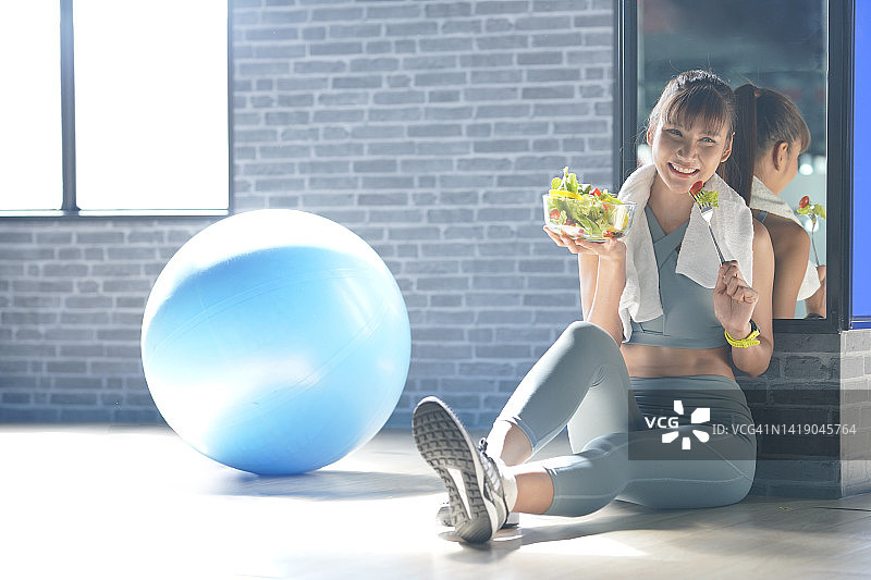 在体育馆里拿着新鲜沙拉的女人图片素材