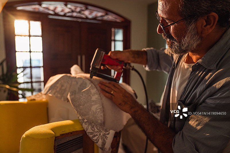 中年男人在其客厅里装饰扶手椅图片素材