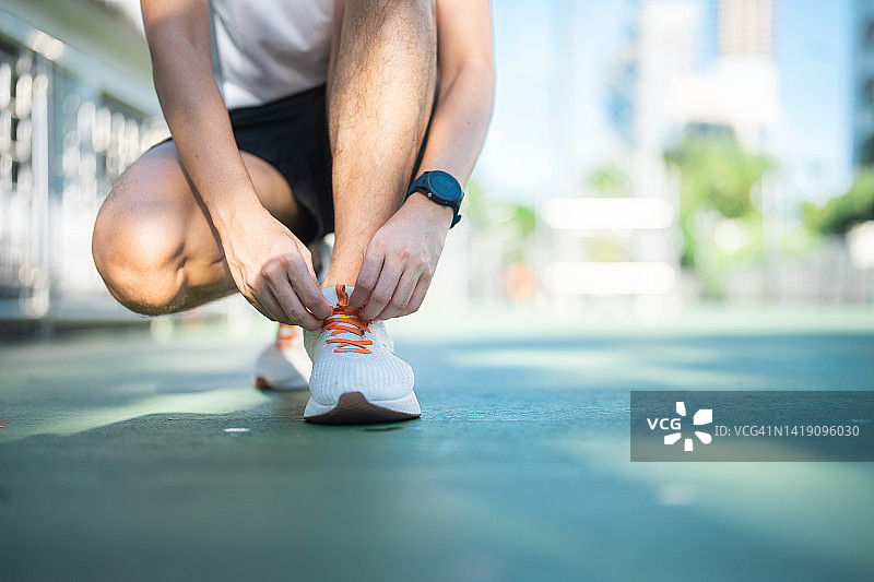 男子在公园慢跑前系跑鞋鞋带特写图片素材