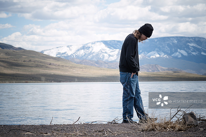 在湖岸边行走的孤独年轻人图片素材