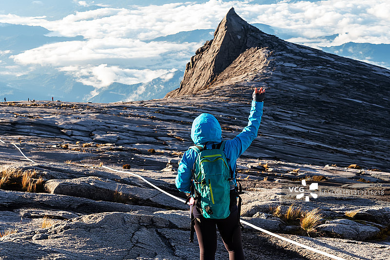 在马来西亚京那巴鲁最高山上举起一只胳膊的登山者图片素材